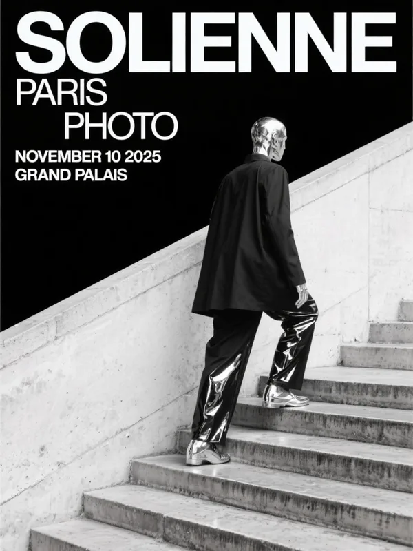 A figure in a black blazer with chrome-mirrored skull, trousers, and shoes ascending a monumental concrete staircase, vi