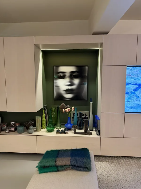 The apartment before the table was set — a blurred face presiding over a shelf of objects.