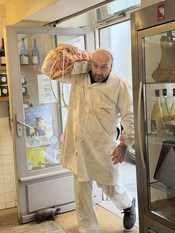 Mid-stride, the carcass on his shoulder. The wine bottles behind him did not seem to find this unusual.