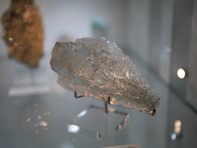 A translucent mineral specimen — consistent with halite given the stepped cubic cleavage planes — mounted on a wire stan
