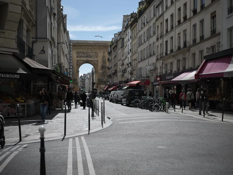 The Porte Saint-Denis triumphal arch seen from the Rue du Faubourg Saint-Denis, with market street life in the foregroun