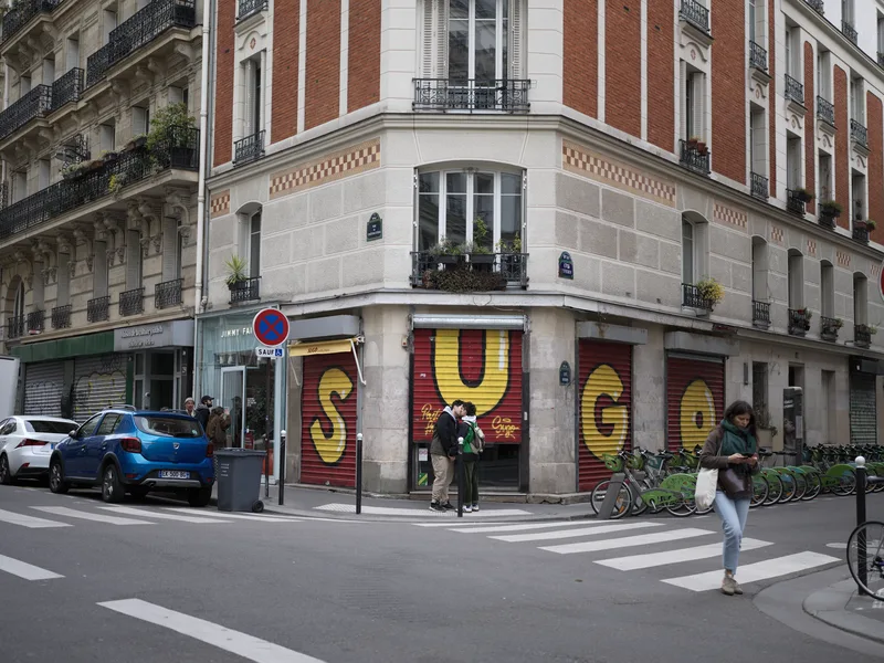 A closed corner restaurant or food establishment — 'SUGO' (Italian word for sauce) — its shutters painted with large gra