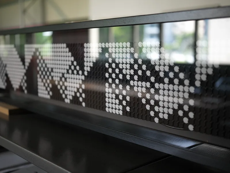 A perforated metal panel displaying a halftone-style dot matrix pattern — likely public signage, architectural screening